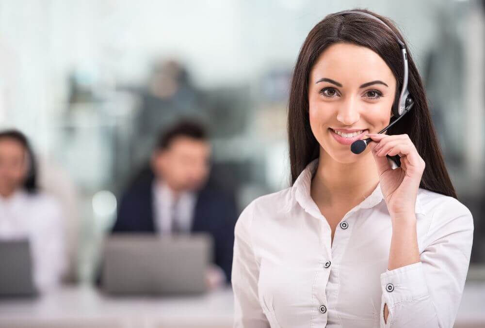 call center agent smiling while taking a call using her headphone