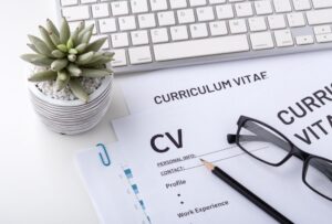 curriculum vitae with glasses, keyboard and a plant
