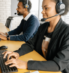 Male and female call center agents in front computer while happily working