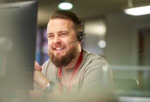 smiling customer service representative facing computer wearing headset